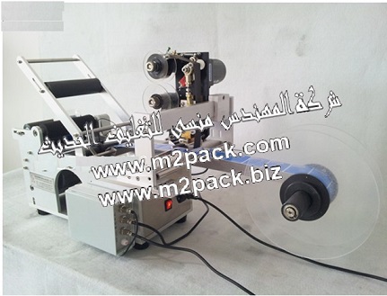 ماكينة لصق العلامات - الشعارات علي الزجاجات الدوارة نصف آتوماتيكية والتي تسمي آيضاً ماكينة لصق الشعارات المصنوعة من البلاستيك الشفاف ملحقة و مزودة بماكينة طباعة تاريخ التى نقدمها نحن شركة المهندس المنسي للتغليف الحديث و الصناعات الهندسيه إم تو باك